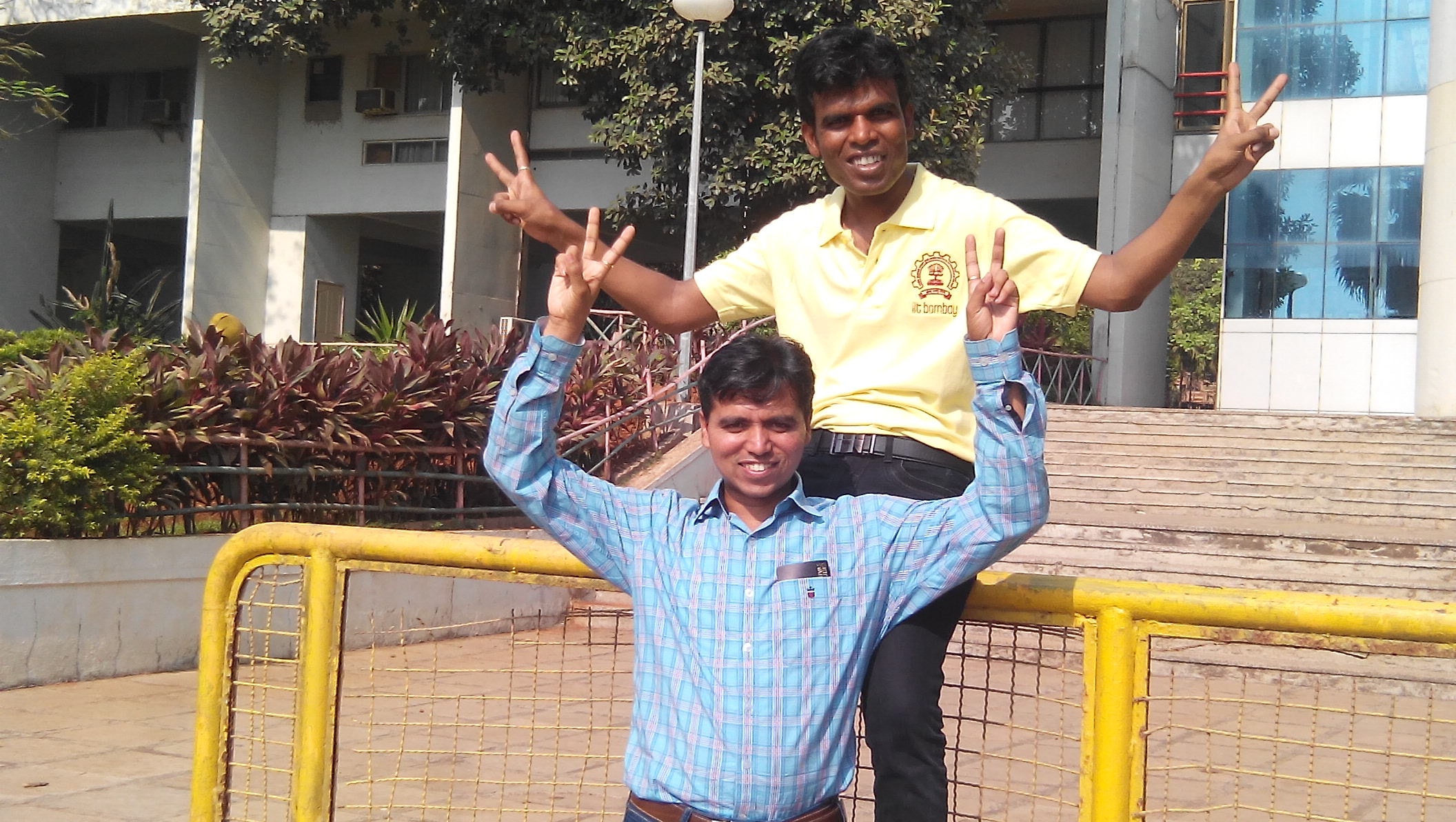 Two friends posing outdoors in front of a campus building
