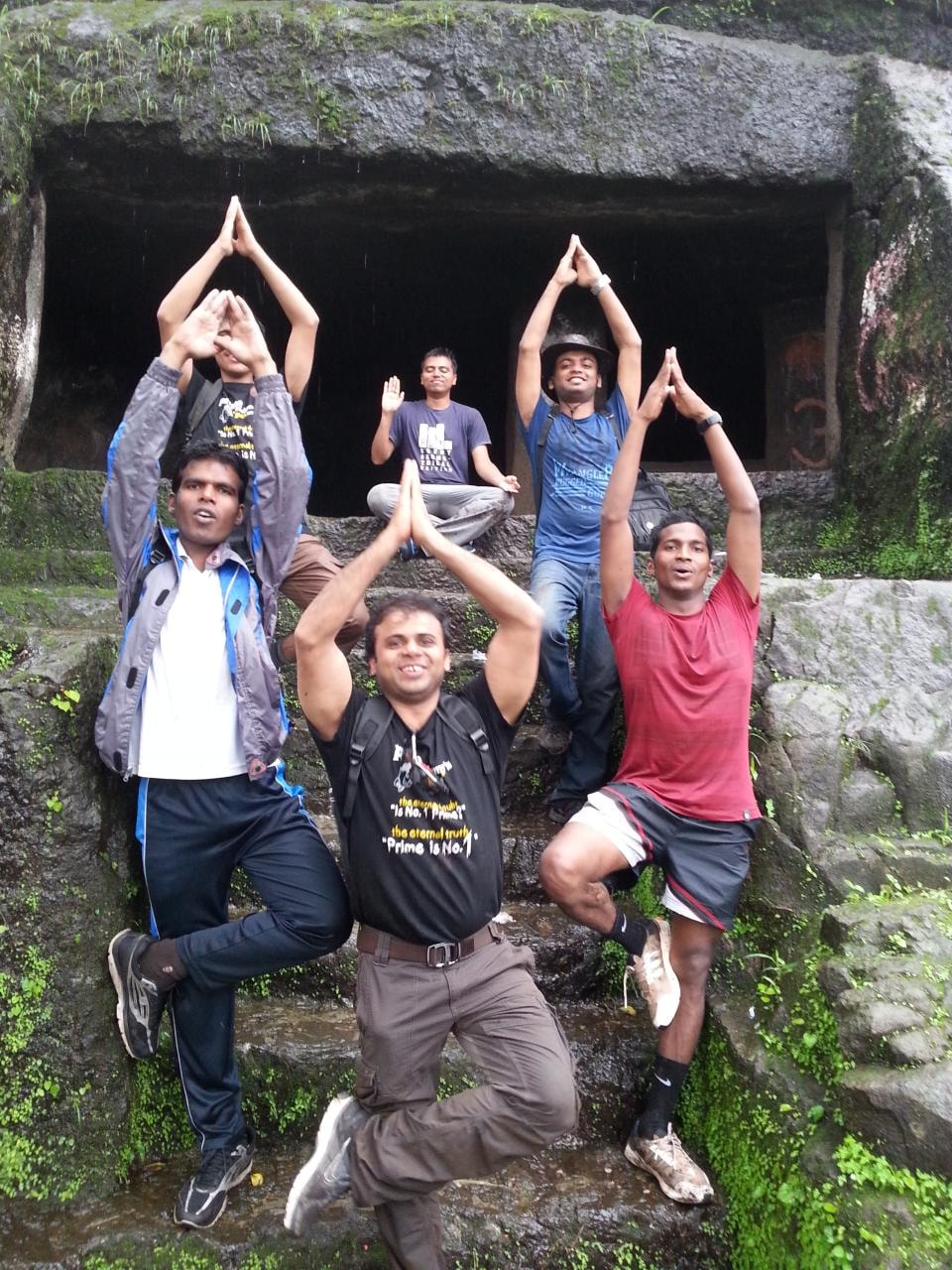 Prime Academy team doing yoga poses on a trek at a historic stone structure