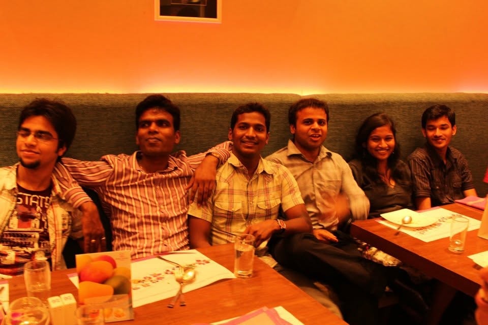 Six friends seated together at a restaurant table